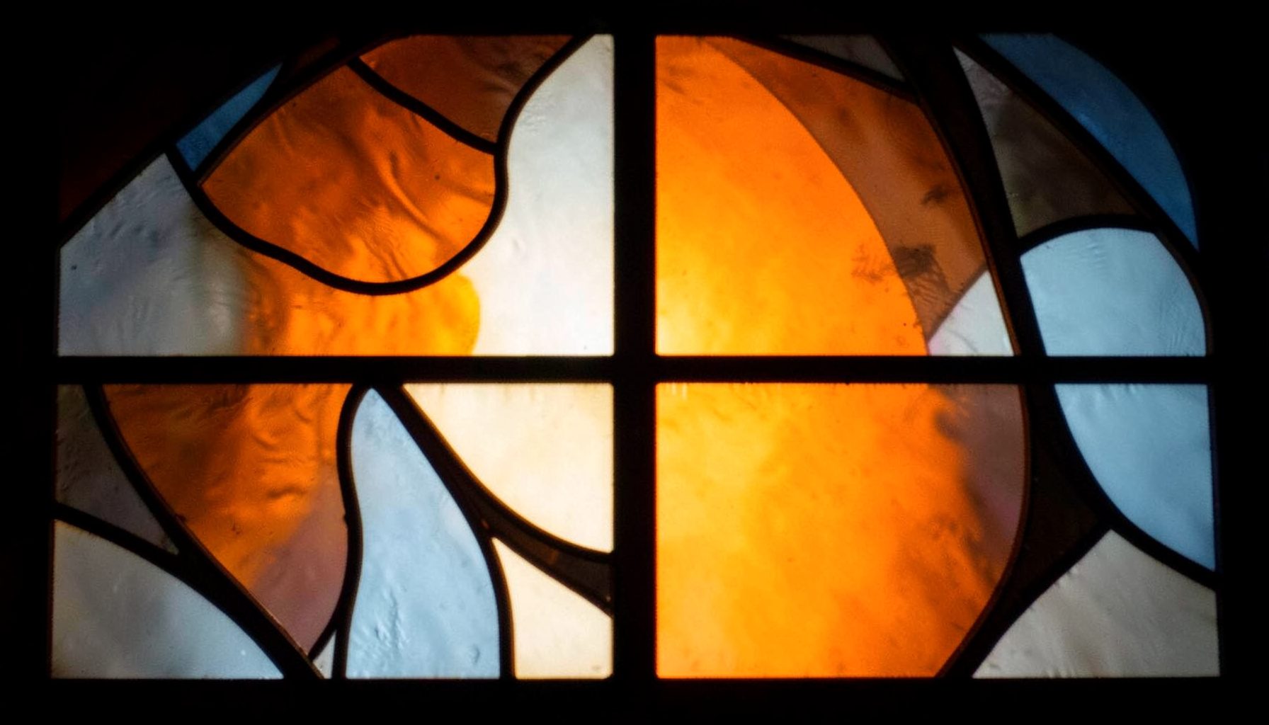 Abstract stained-glass composition in burnt orange, charcoal and soft blue tones, evoking gallery windows with bold leaded segments