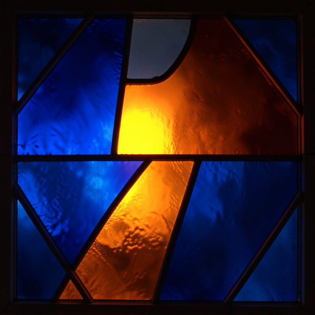 Stained-glass fragment in deep blue and burnt orange, bold leaded segments