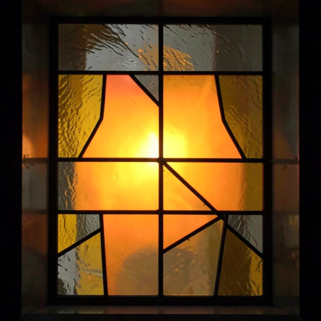 Stained-glass panel in charcoal and ochre, asymmetric leaded grid