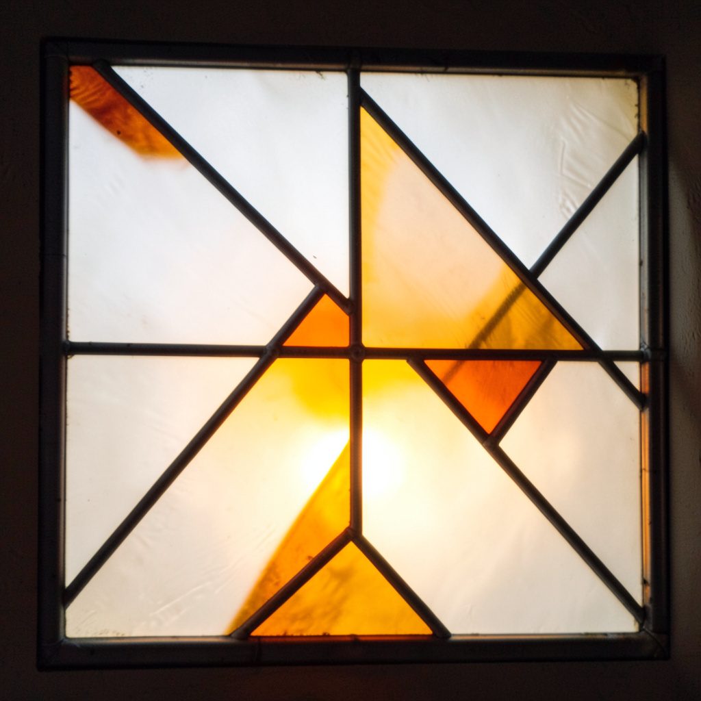 Stained-glass fragment in soft white and amber, geometric leaded lines