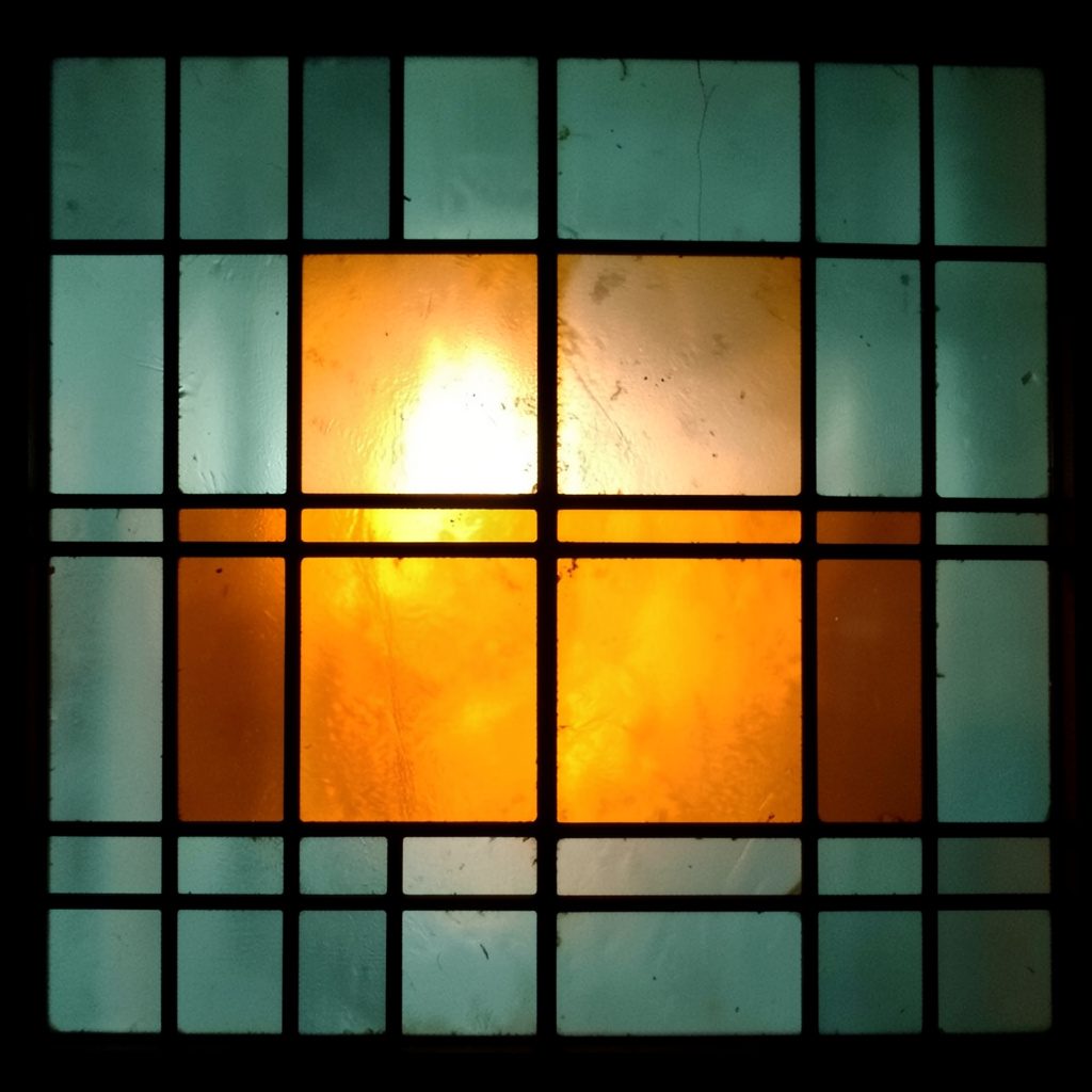 Stained-glass composition in muted teal and burnt orange, rectangular grid