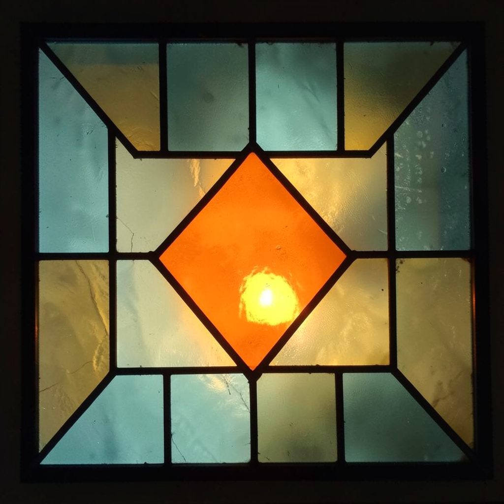 Stained-glass square in muted teal and ochre, geometric layout