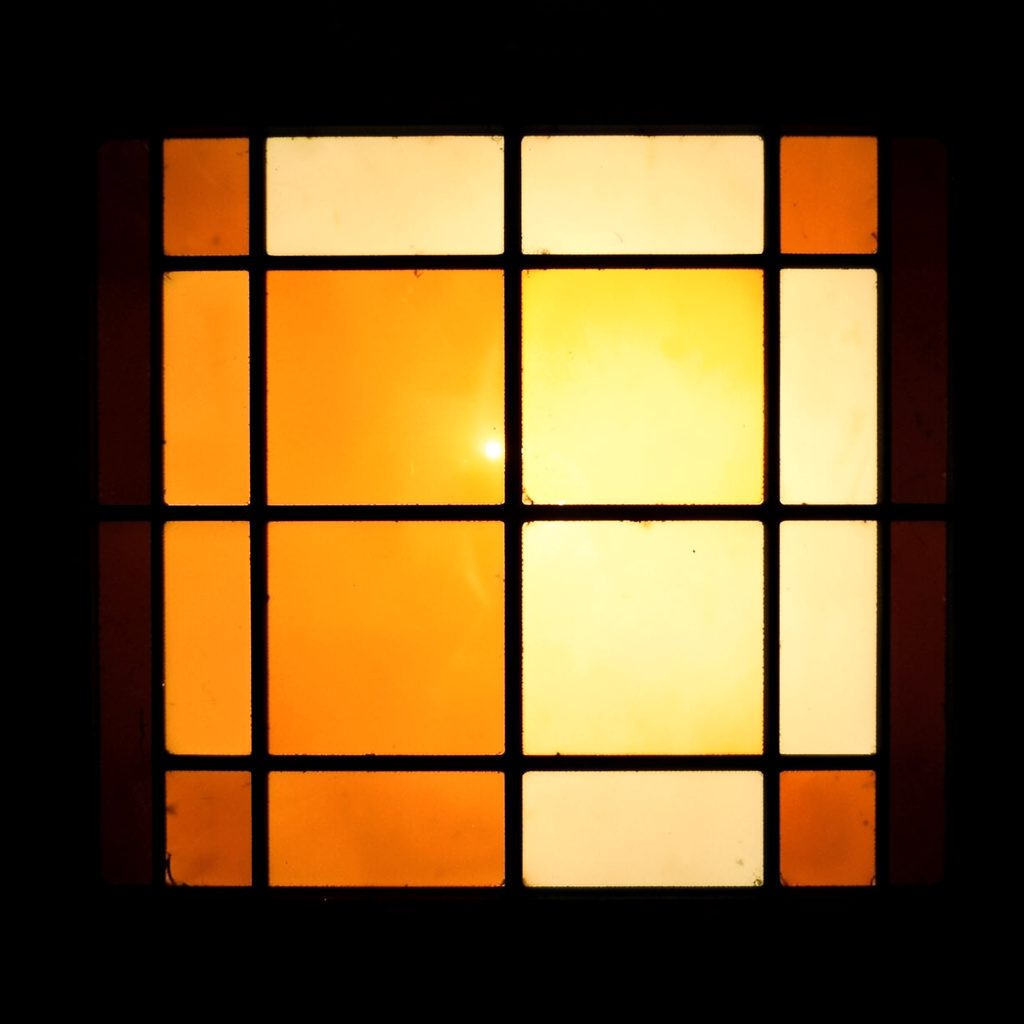 Stained-glass square in burnt orange and pale ivory, simple leaded grid