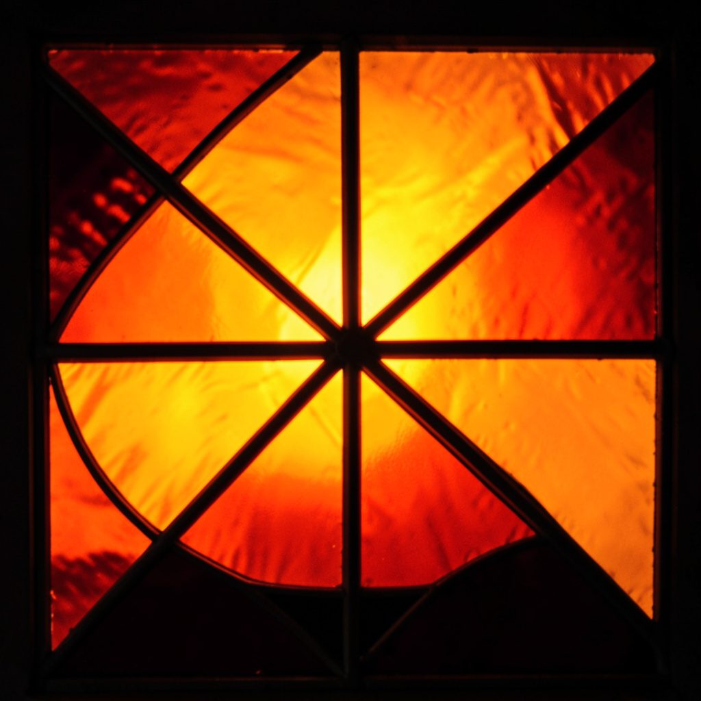 A bold stained-glass composition with deep blue, warm amber, and red segments, creating an elegant and contemplative mood